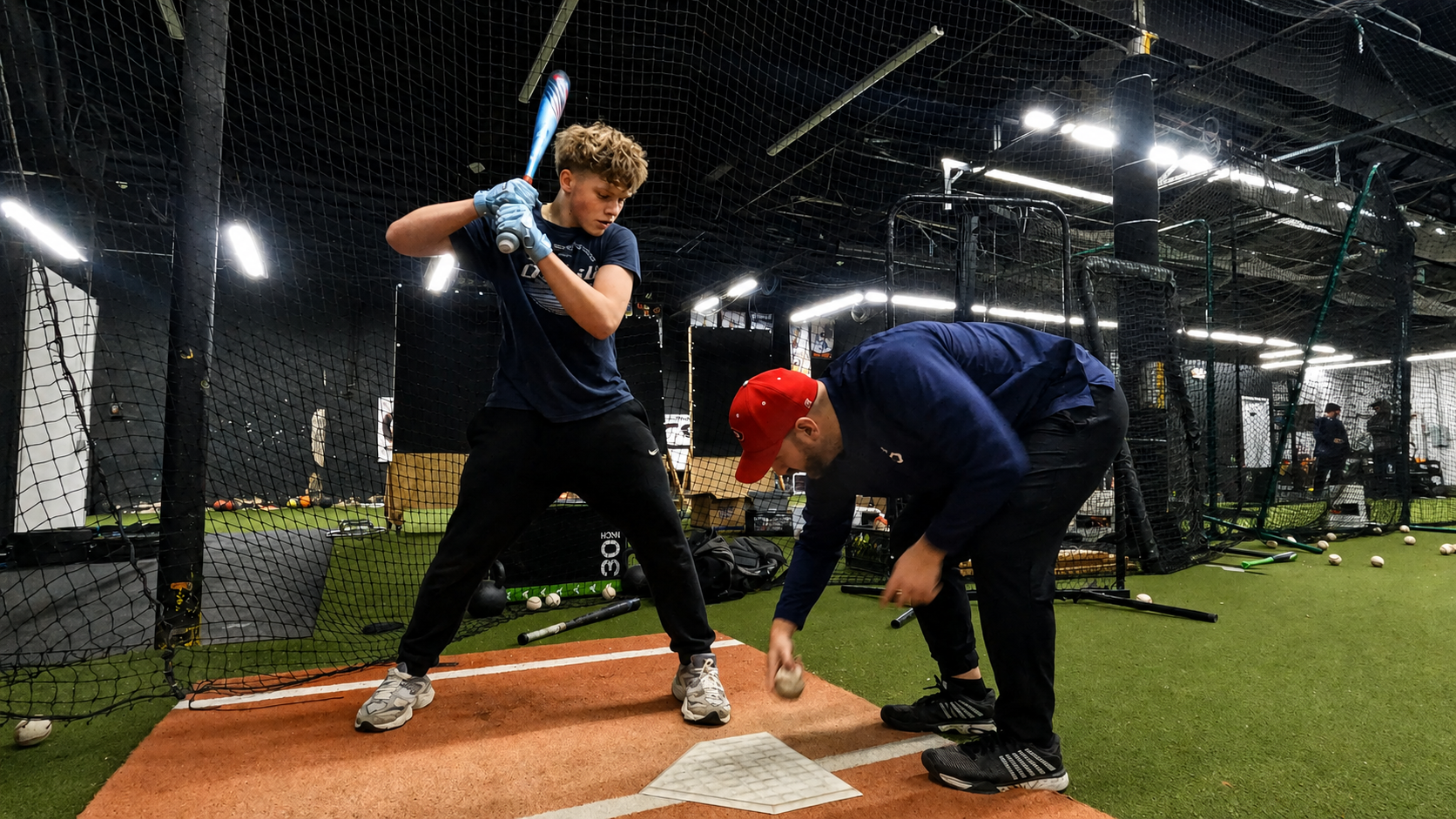 Coach Steve positioning a young hitter's lower half and footwork at home plate during a private session