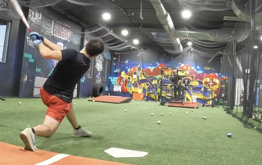 Pitching machine feeding a hitter in an indoor cage